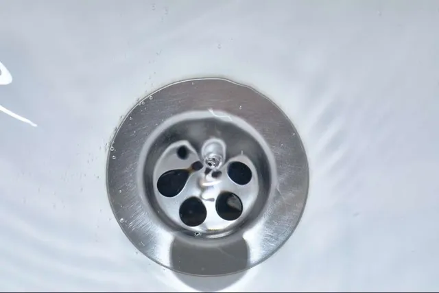 A close up of a sink drain with water running down it.